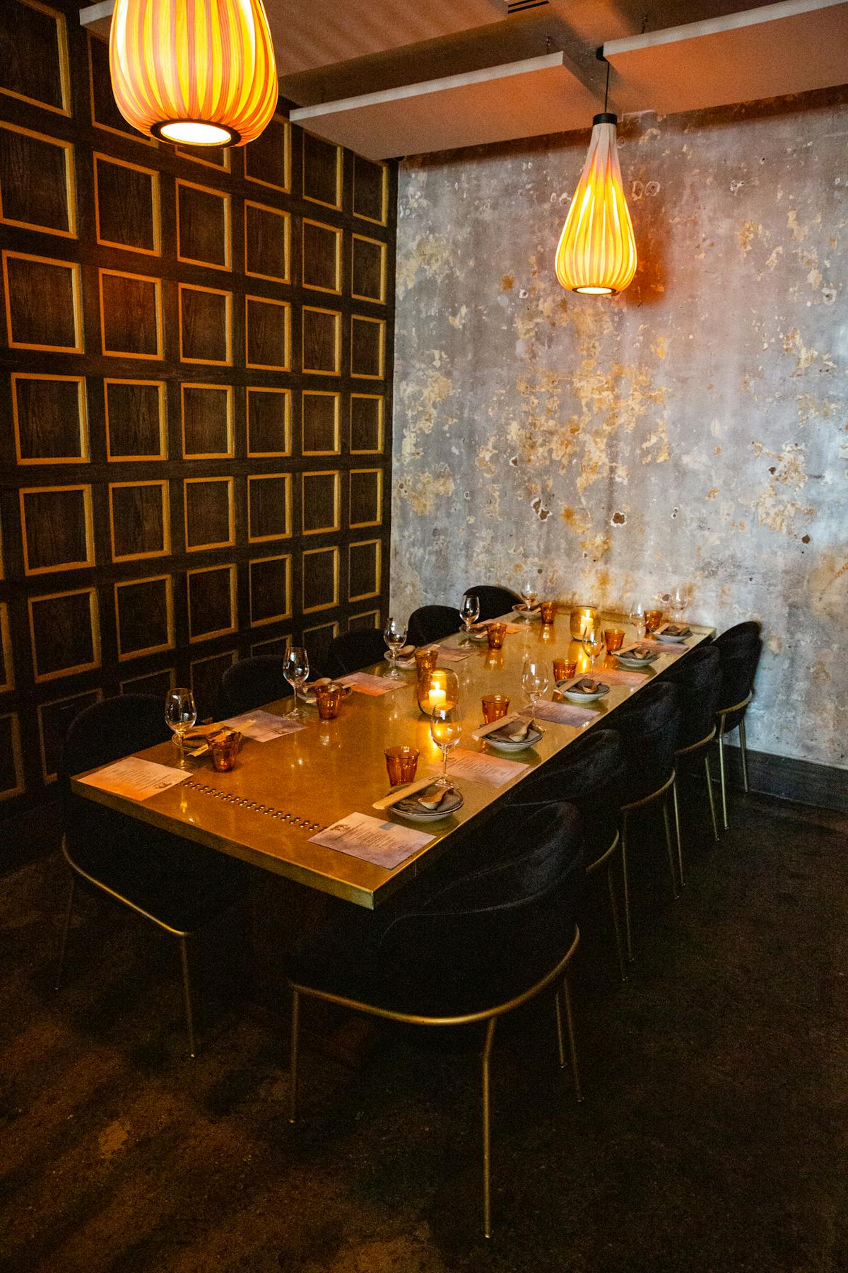 a private dining room with a brass table with black chairs