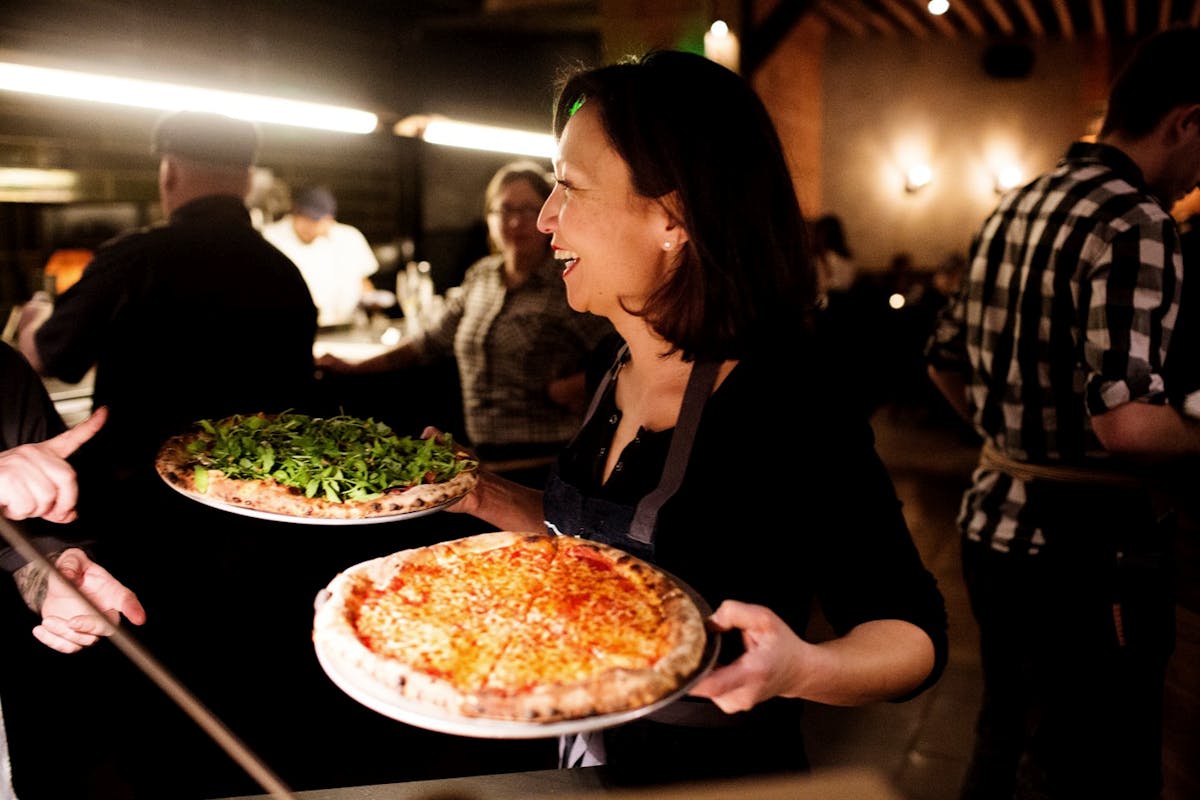 Chef Ann Kim carrying two pizzas