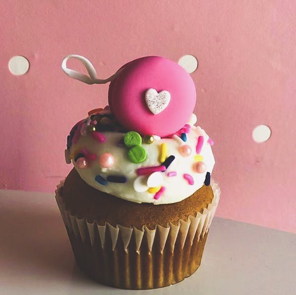 a closeup of a cupcake topped with sweet sprinkles and a heart shaped figure