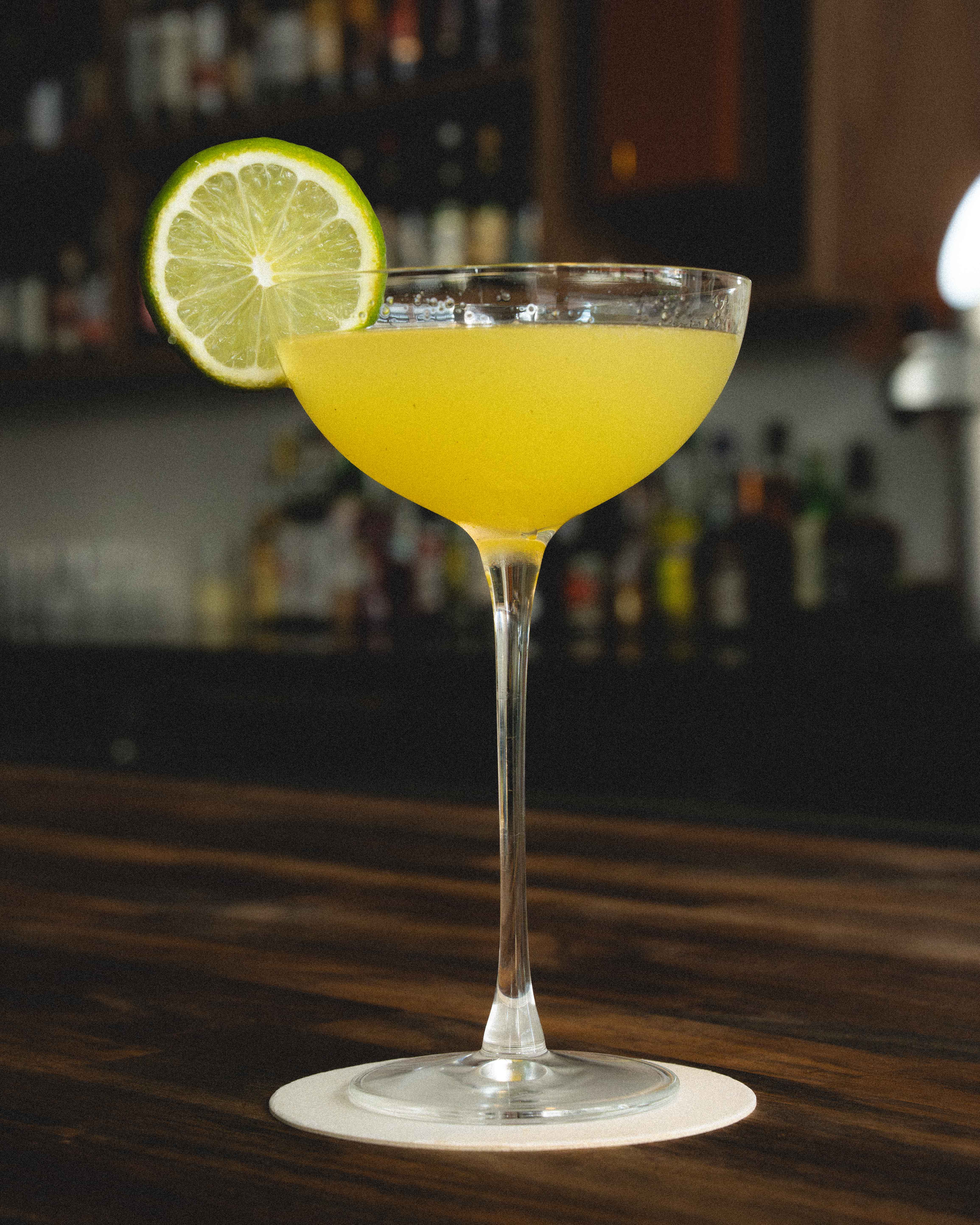 a glass with yellow liquid and a lime slice on top