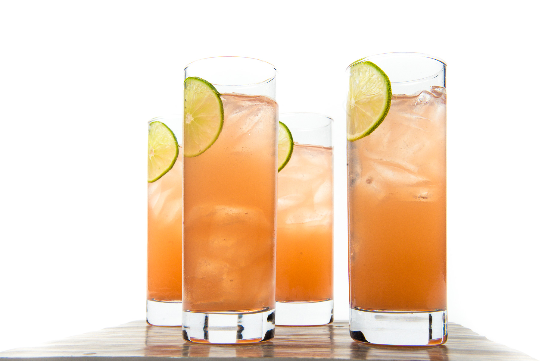 a group of glasses with liquid and lime slices