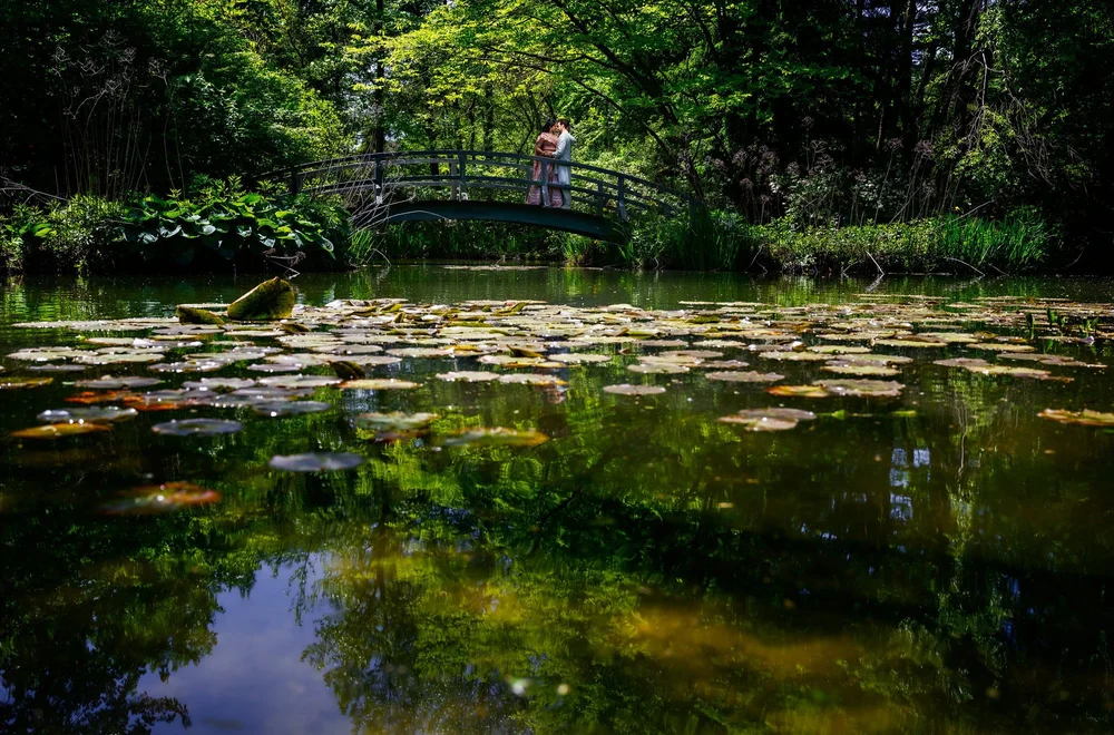 a couple standing on a bridge over a pond
