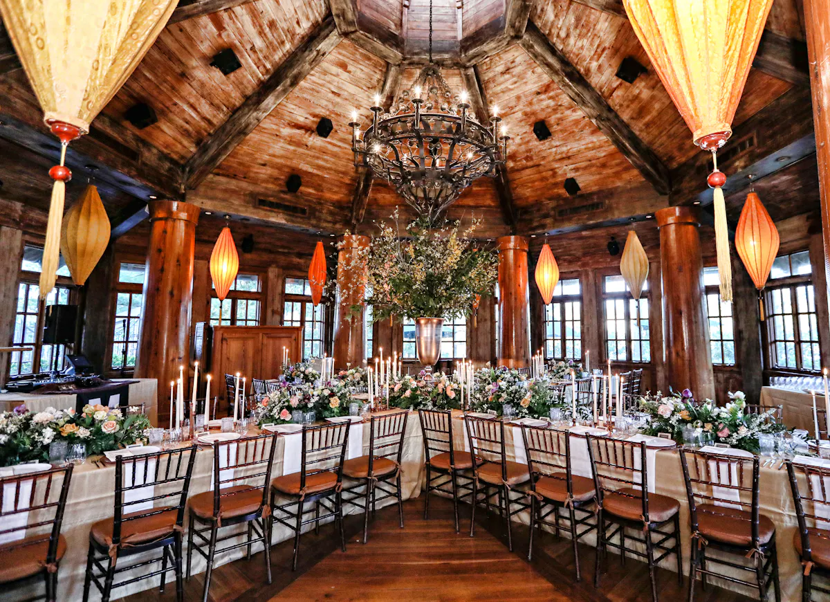 a room with a chandelier and tables with flowers and candles