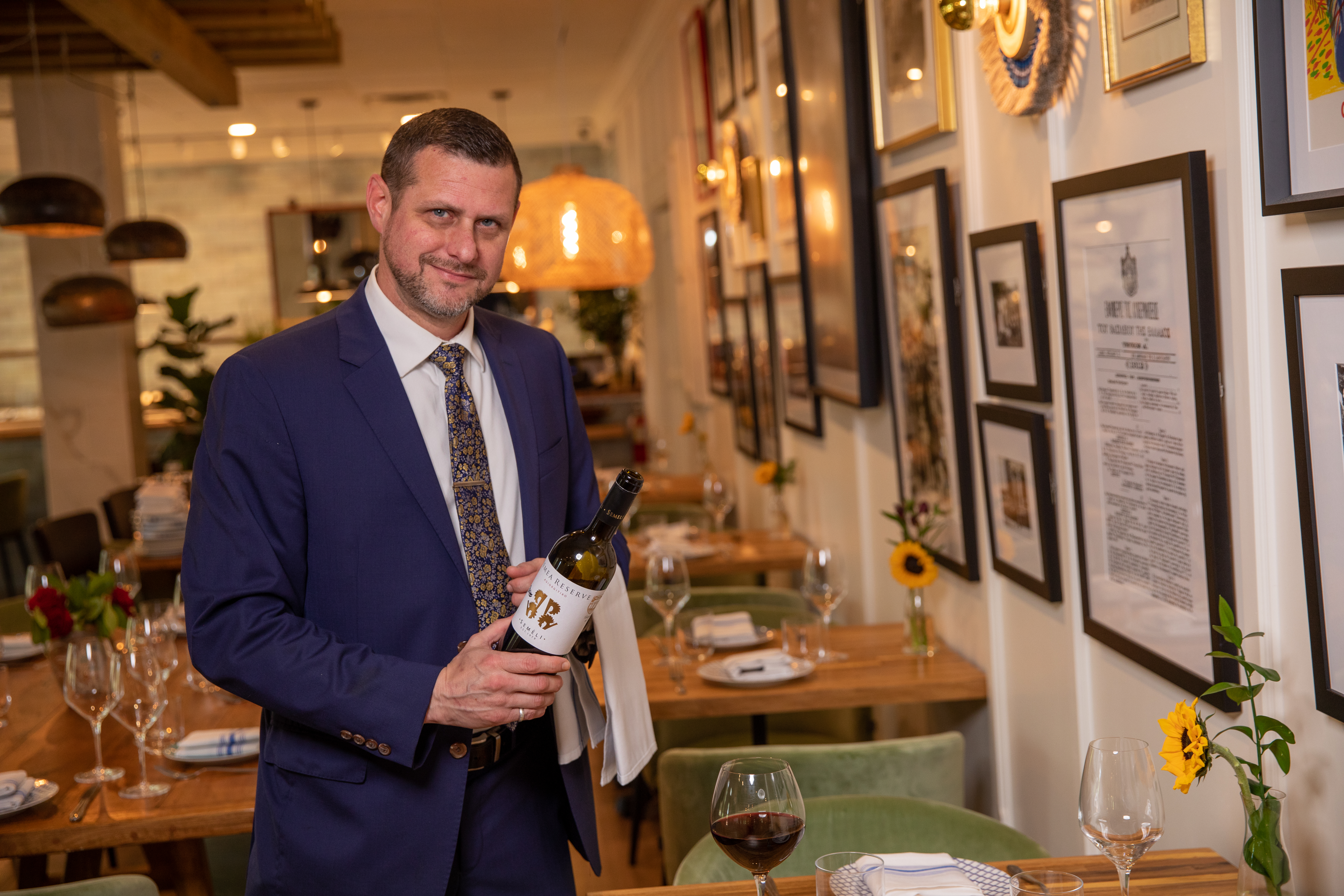 a person wearing a suit and tie holding a wine glass