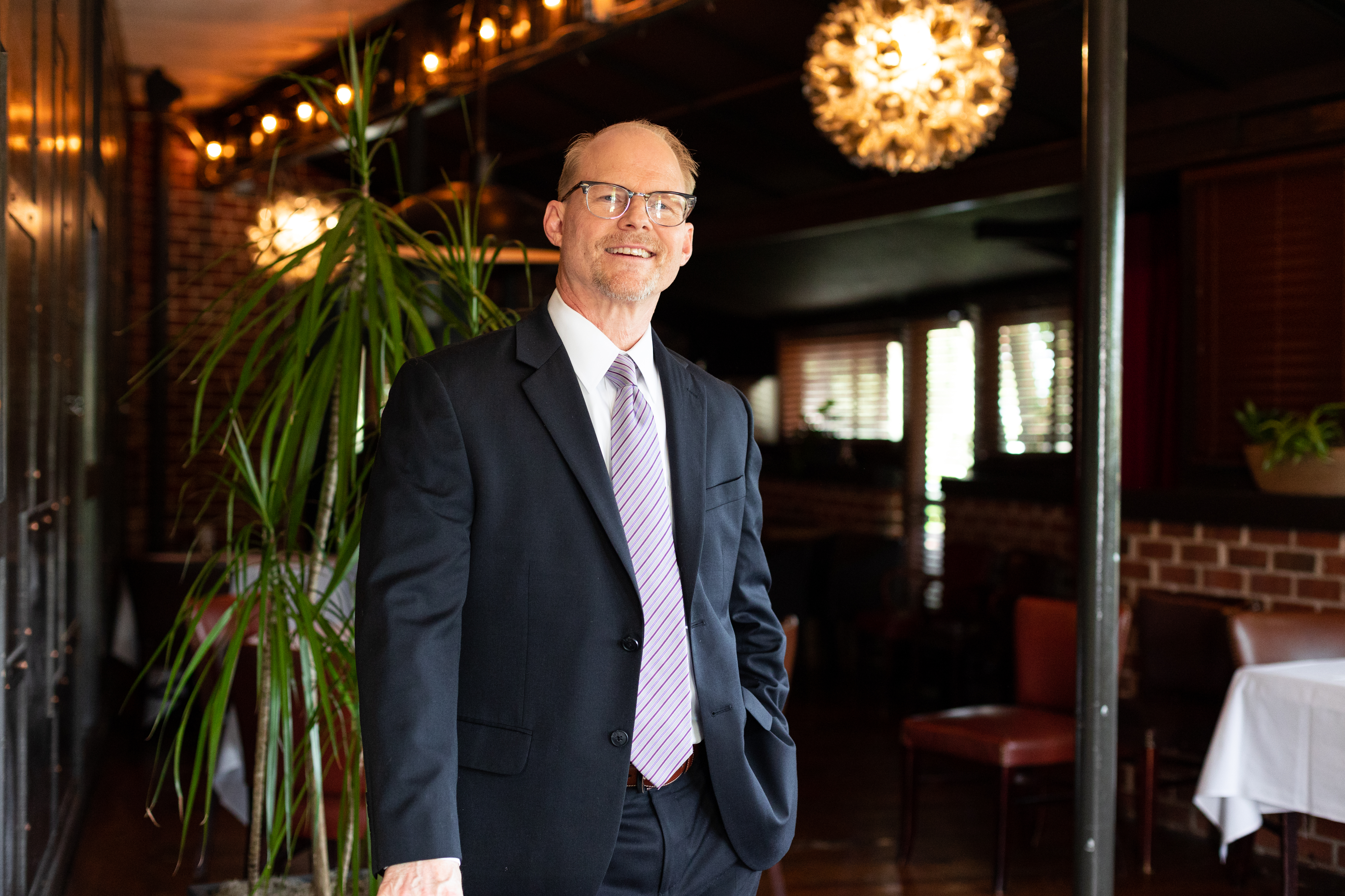a man wearing a suit and tie standing in front of a building
