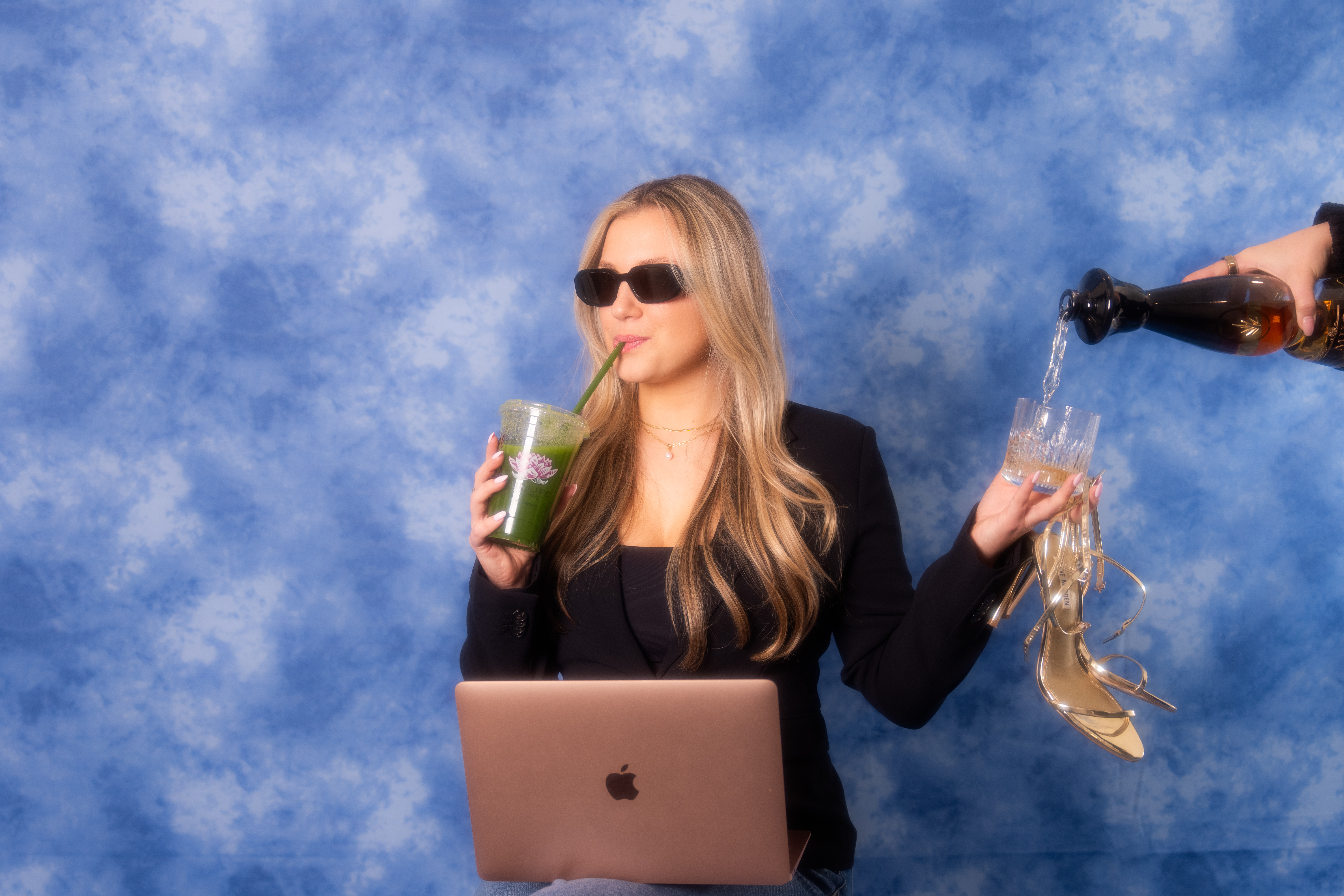 a woman holding a drink and a laptop