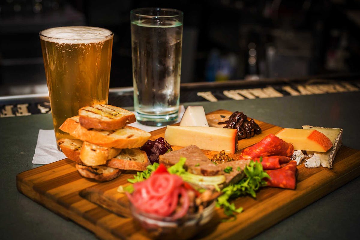 a glass of beer on a wooden cutting board