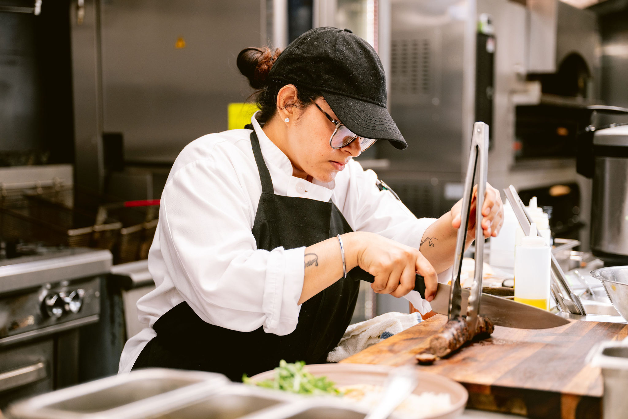 a woman in a black hat cutting meat