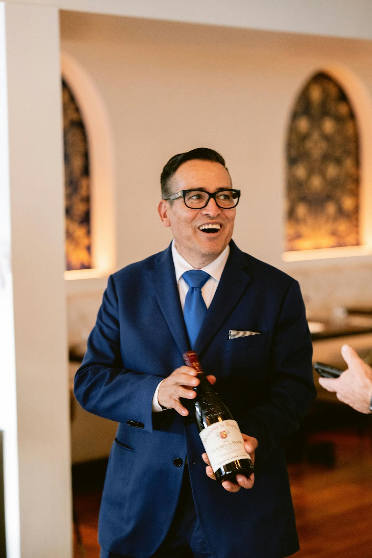 a man wearing a suit and tie holding a glass of wine