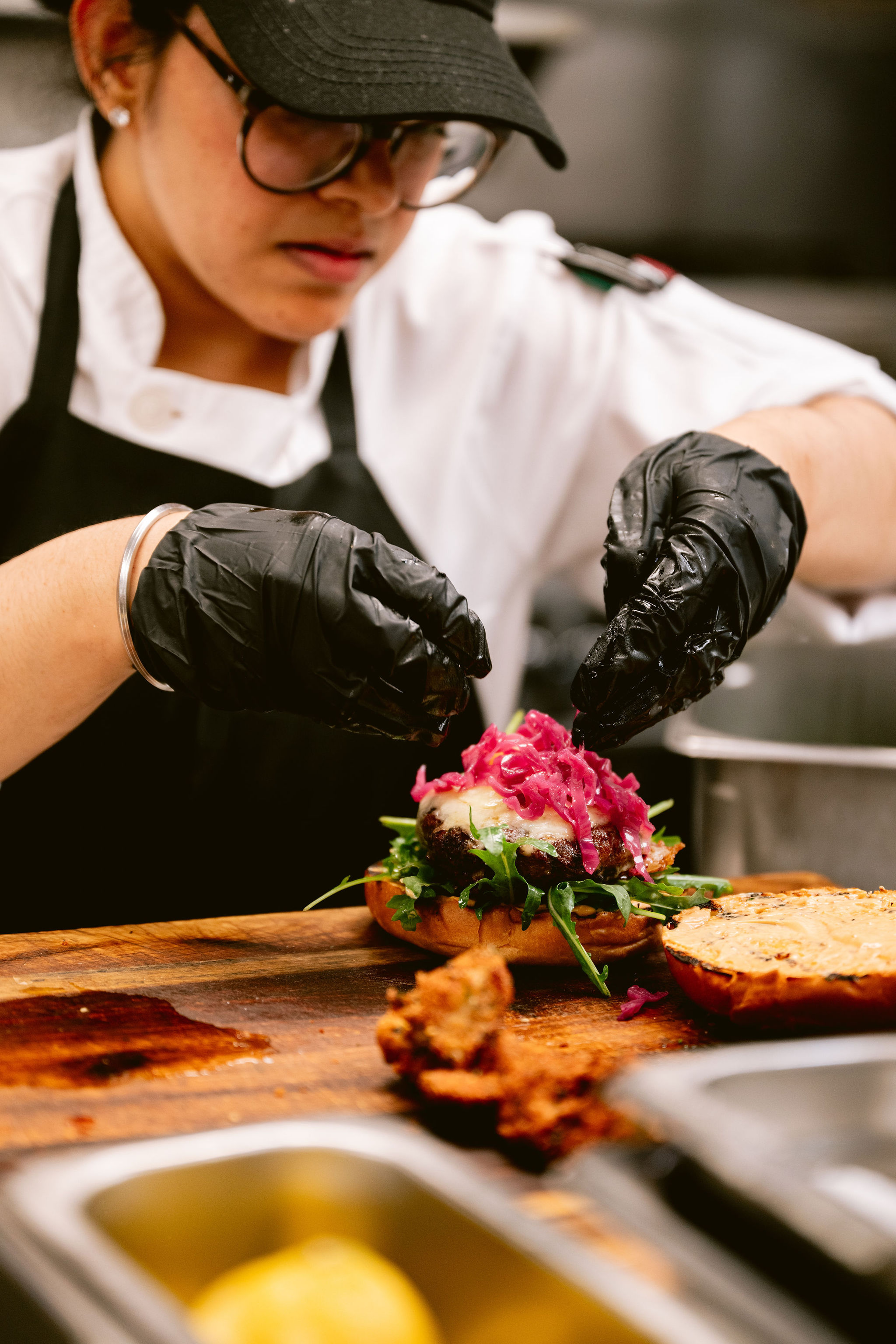 a person in a chef's kitchen making a burger