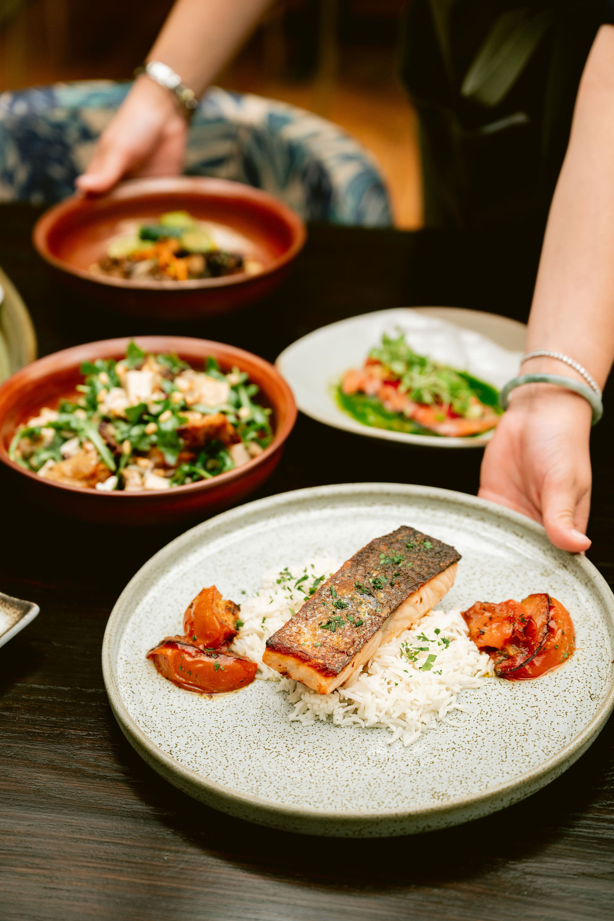 a person holding a plate of food on a table
