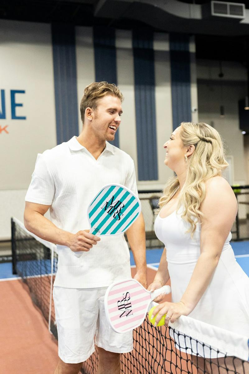 Couple holding pickleball paddles at the net at Dink & Dine Pickle Park