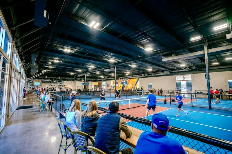 Guests watching from courtside seating along the indoor courts at Dink & Dine Pickle Park