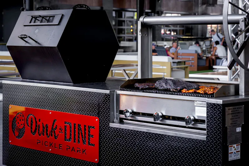 Smoked meats on the Dink & Dine branded smoker for Dink Dive BBQ catering at Dink & Dine Pickle Park