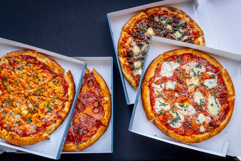 Pizzas in open takeout boxes for the Pizzas in the Park catering package at Dink & Dine Pickle Park