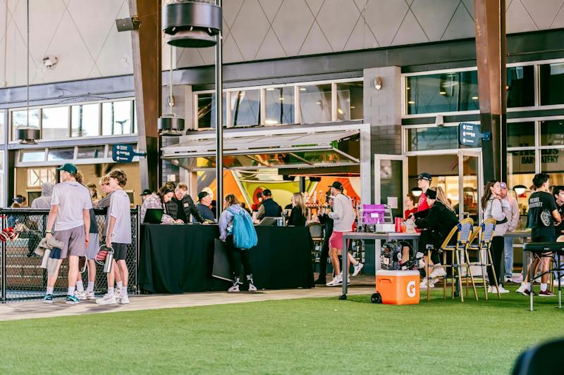 Guests gathered at tables on the turf lawn at Dink & Dine Pickle Park