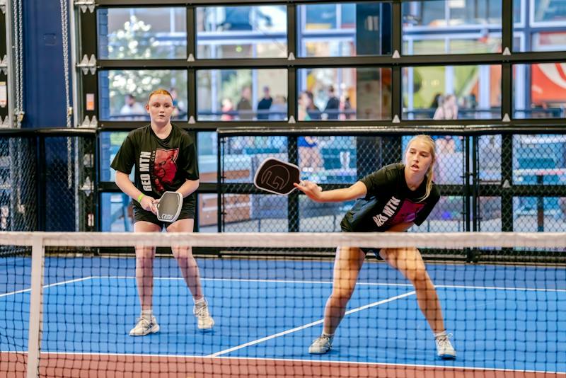 Doubles players at the net during a rally at Dink & Dine Pickle Park