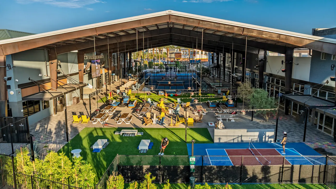Aerial view of the covered Pickle Park lawn and outdoor courts at golden hour
