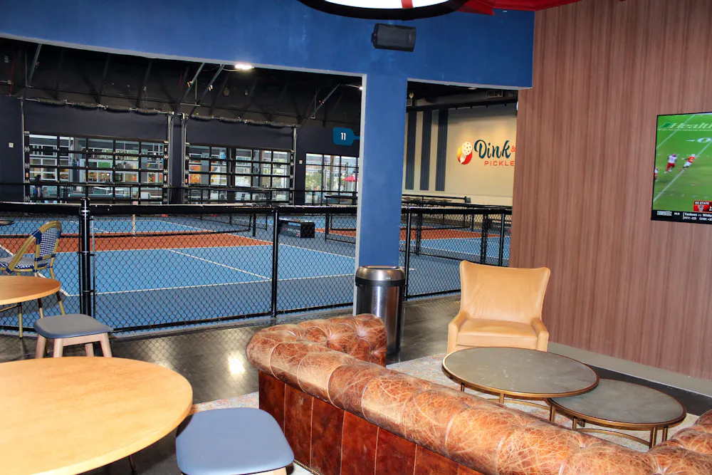 The Clubhouse lounge with leather seating overlooking indoor pickleball courts