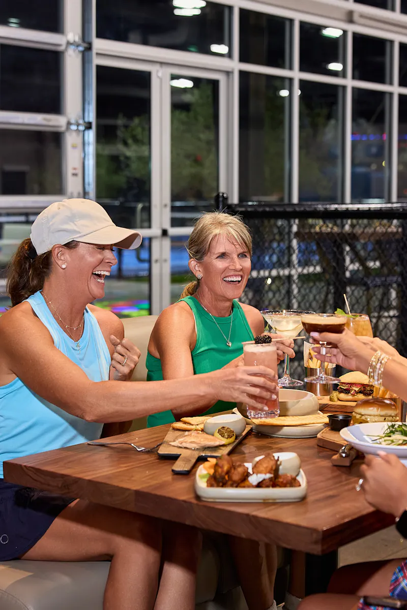 Friends sharing a toast over dinner courtside