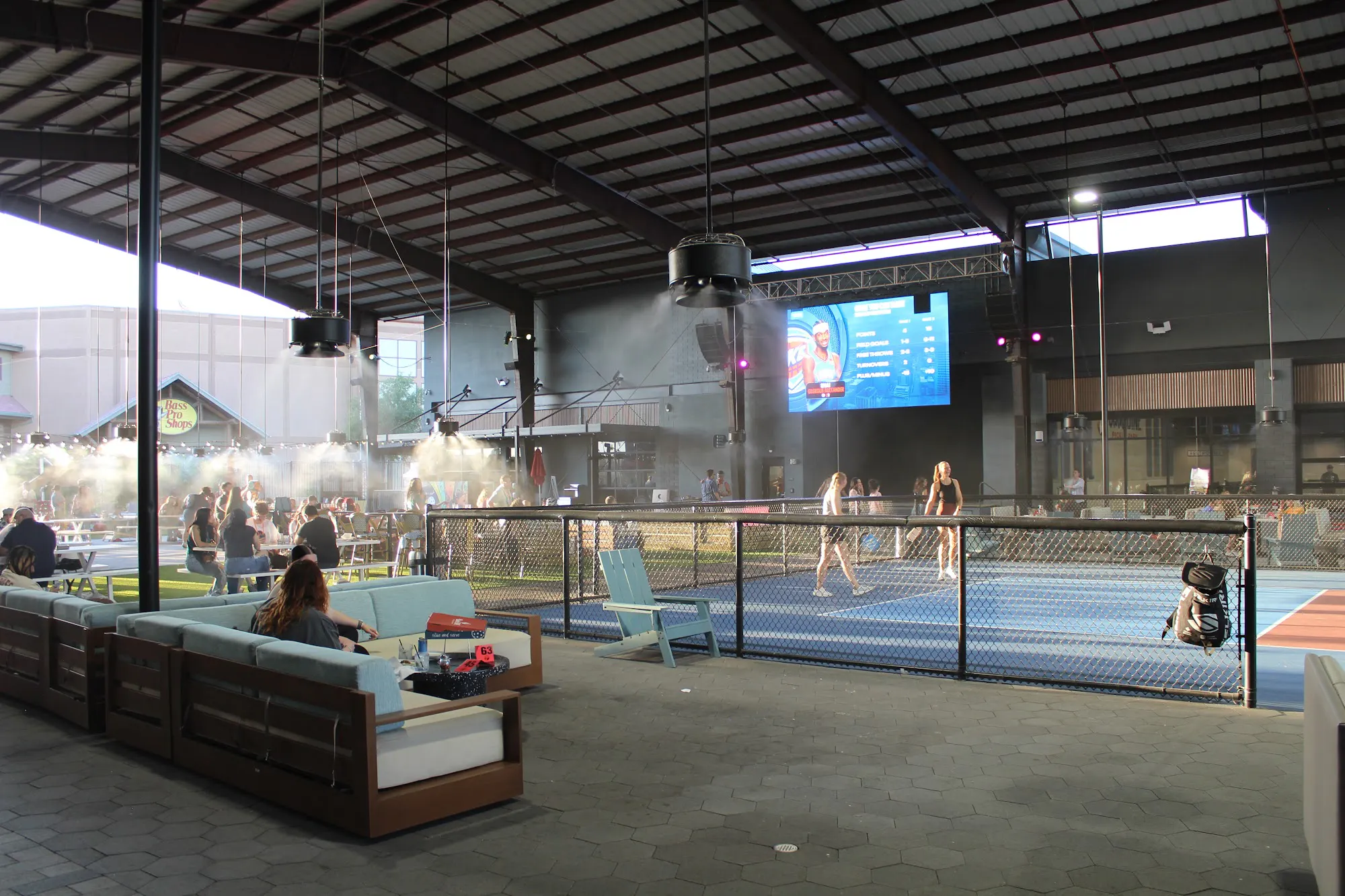 The jumbo screen over the covered, misted Pickle Park with lounge seating and outdoor courts