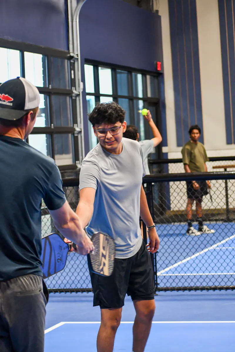 Two players tapping paddles after a rally on an indoor court