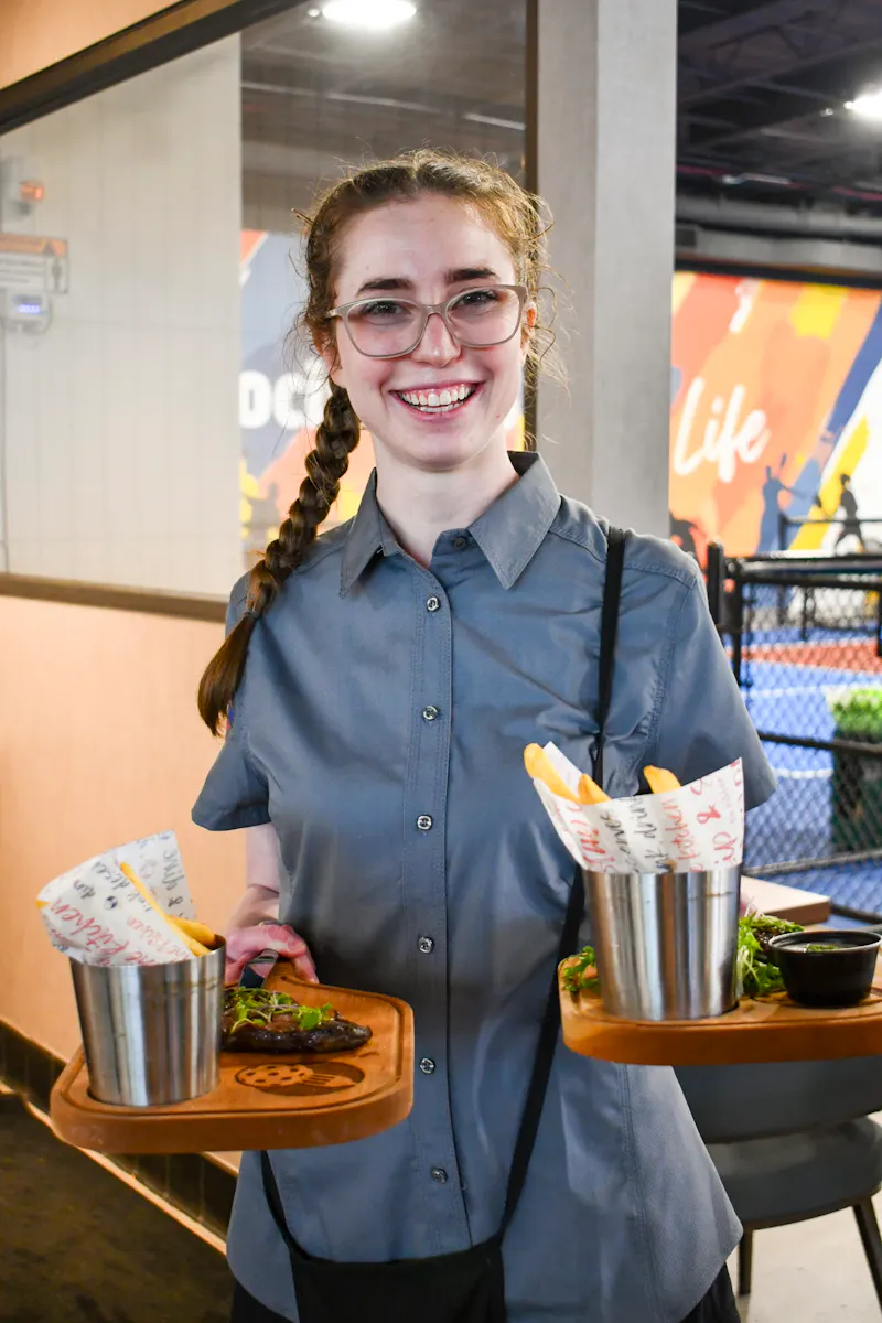 Smiling server bringing fries courtside