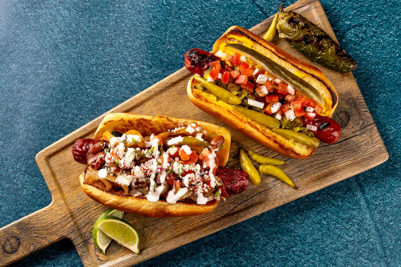 Two loaded hot dogs on a wooden board