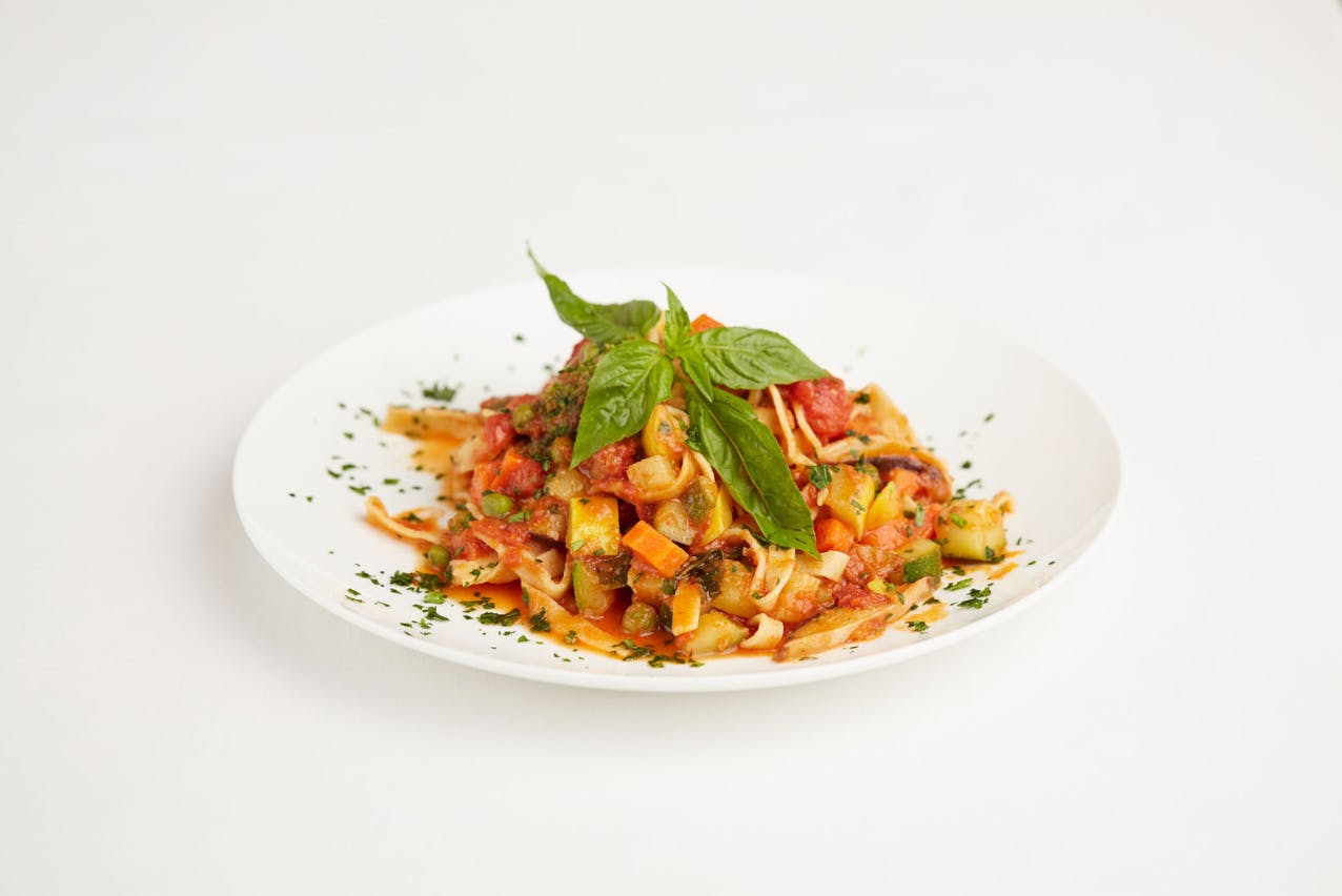 a plate of food with pasta, vegetables and greens.