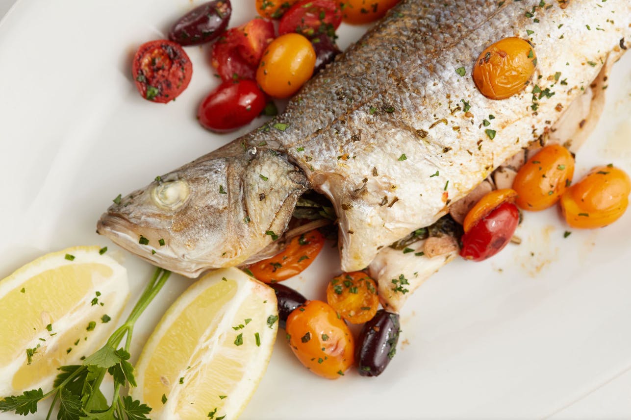 a plate of fish, lemon and assorted types of food