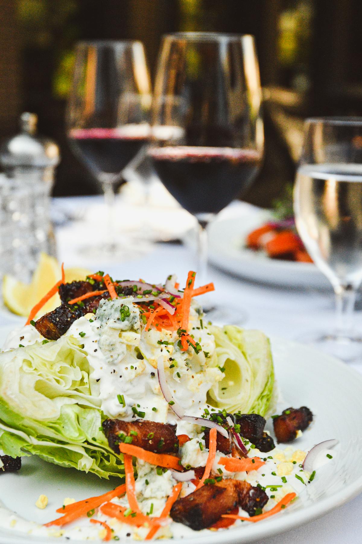 a close up of a plate of salad and a glass of wine
