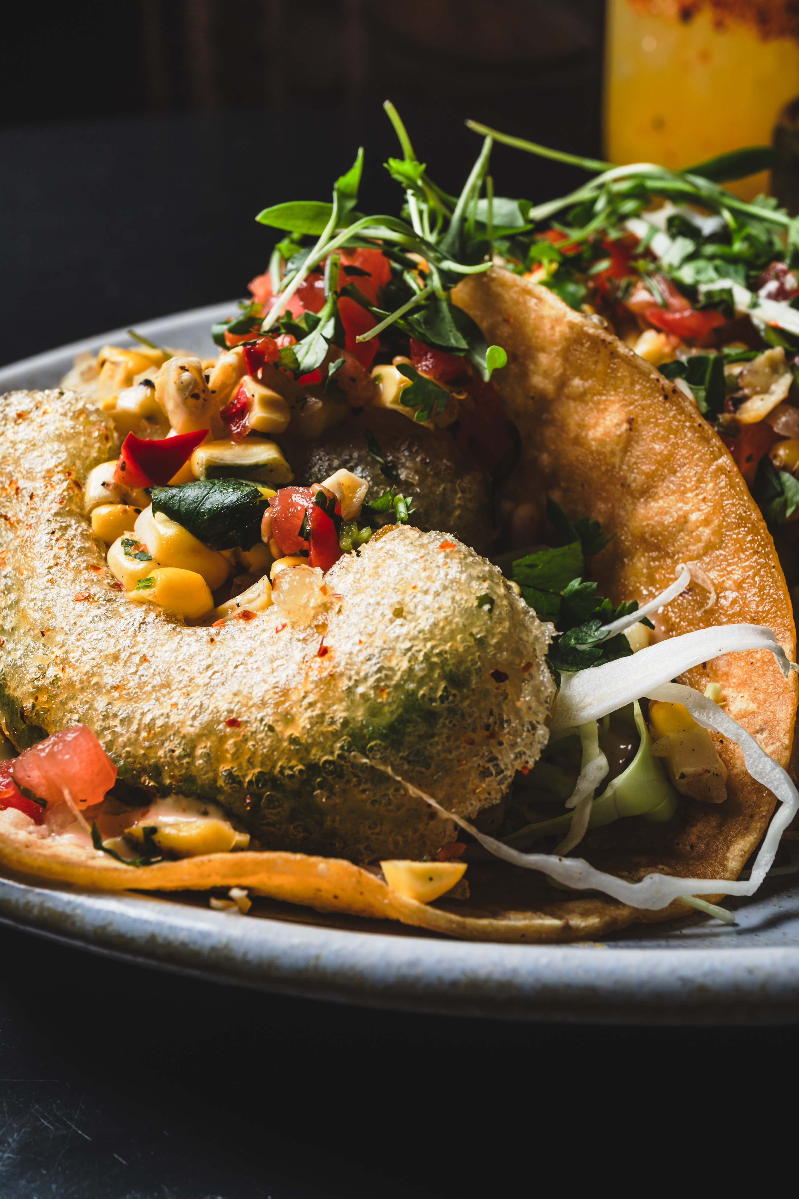 Corn taco layered with Mexican street corn, fresh herbs, shredded cabbage, and a light crispy shell topping at Mijo Modern Mexican.