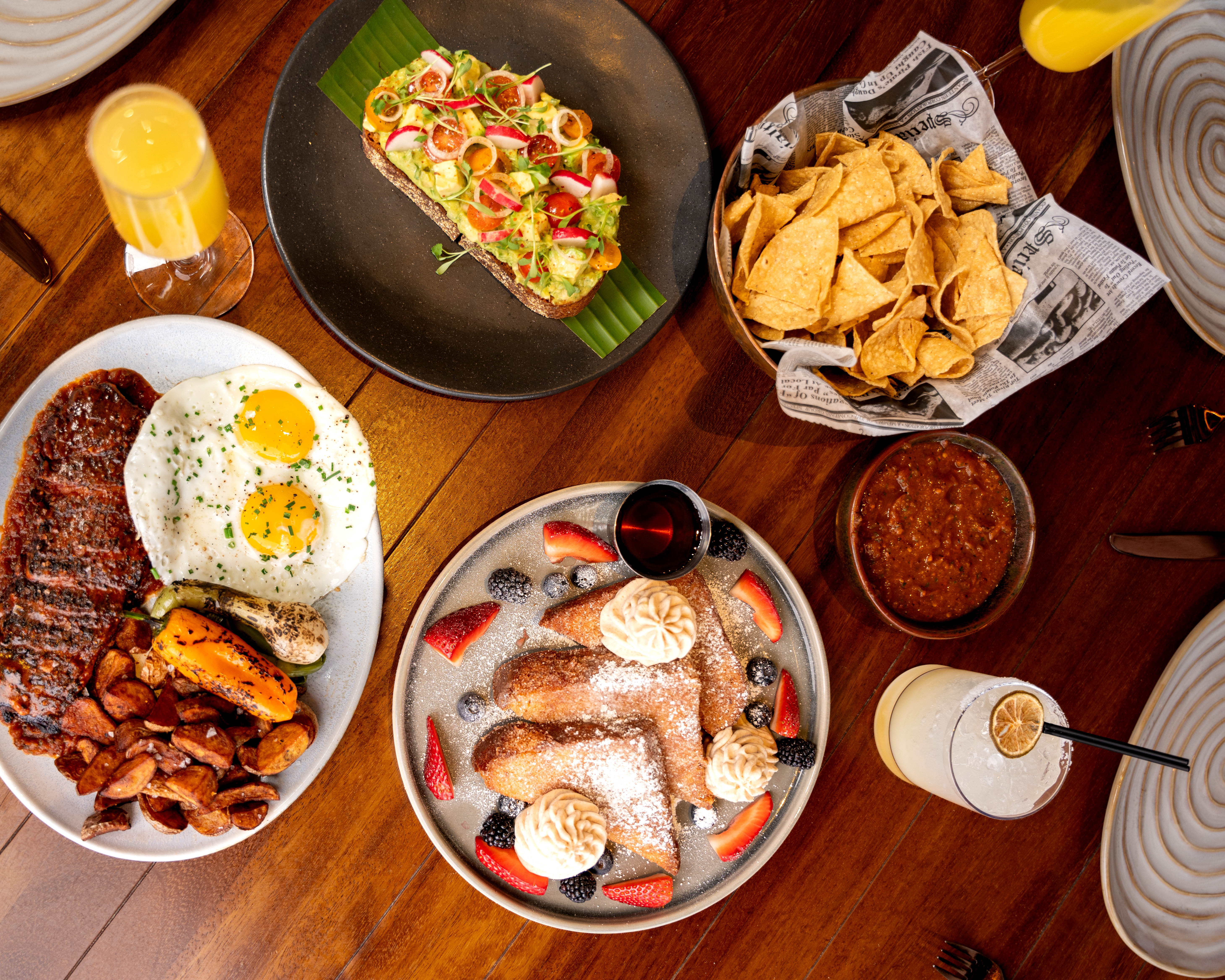 brunch spread featuring churro french toast, avocado toast, and steak and eggs 