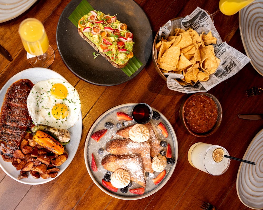 brunch spread featuring churro french toast, avocado toast, and steak and eggs