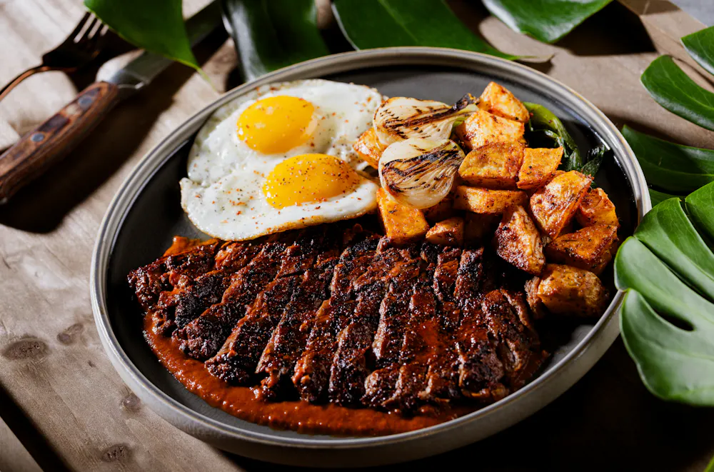 Ranchero steak and eggs with crispy breakfast potatoes and grilled onions at Mijo Modern Mexican, a Mexican Summerlin restaurant serving hearty Mexican brunch and one of the best brunch experiences in Las Vegas.