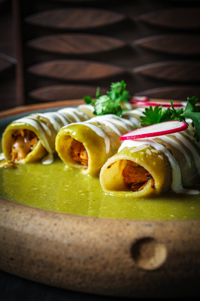 Green chile chicken enchiladas smothered in salsa verde and crema, topped with fresh cilantro and radish slices at Mijo Modern Mexican in Las Vegas.