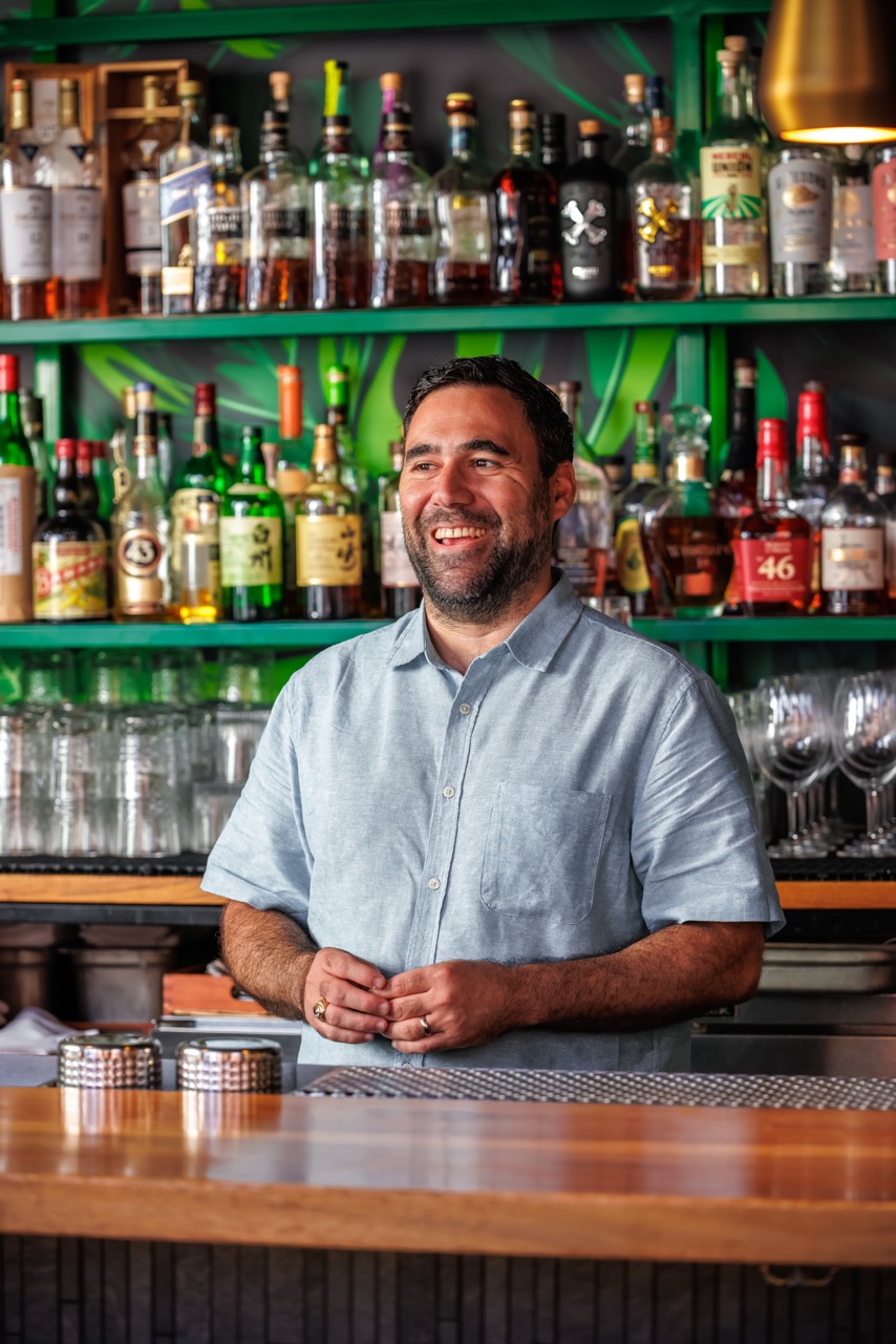 a man standing next to a bottle of beer on a table