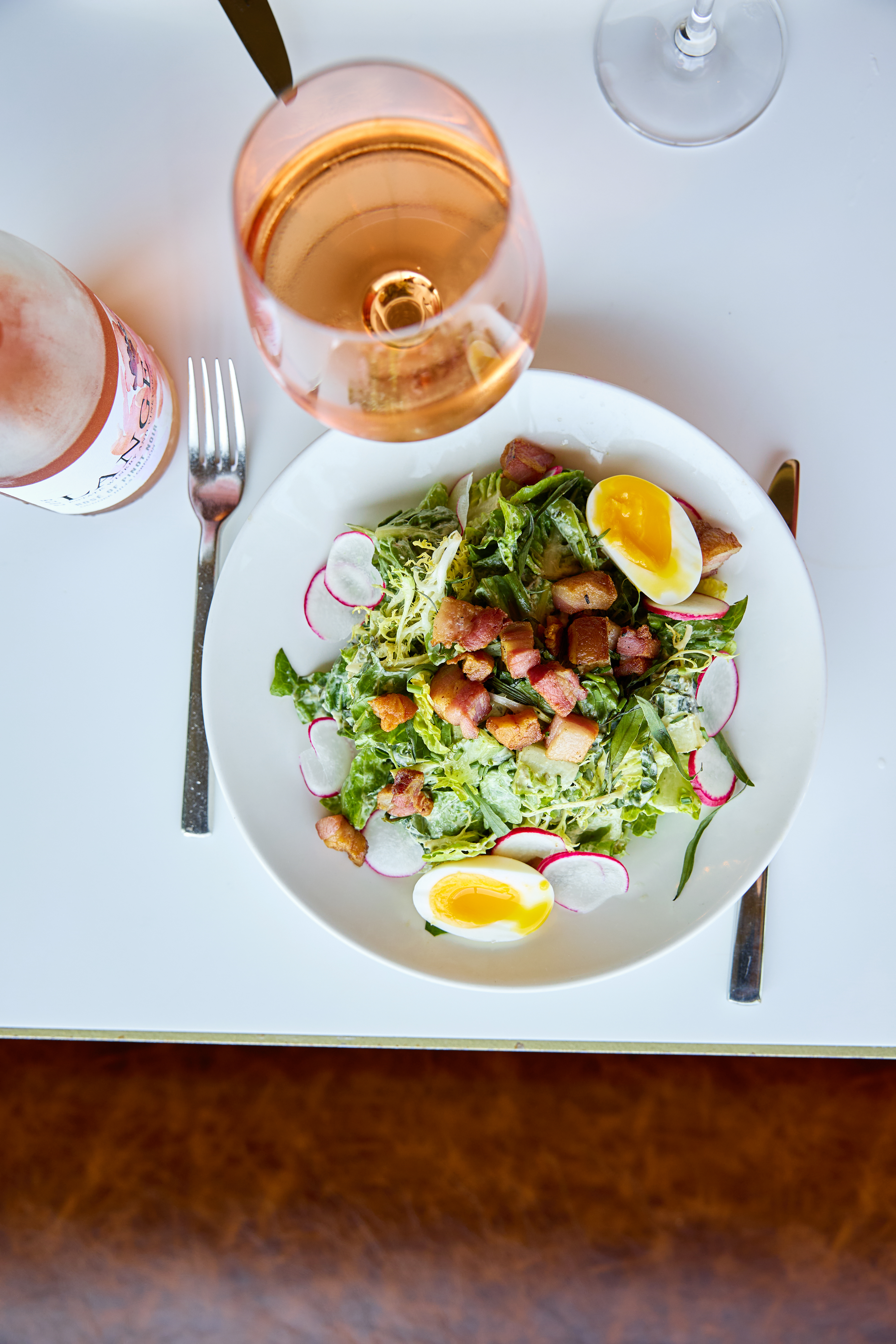 a plate of salad with a glass of wine and fork