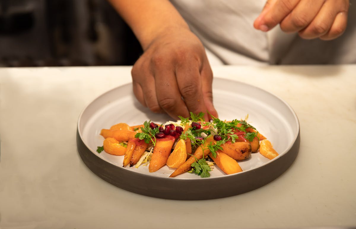 a person holding a plate of food on a table