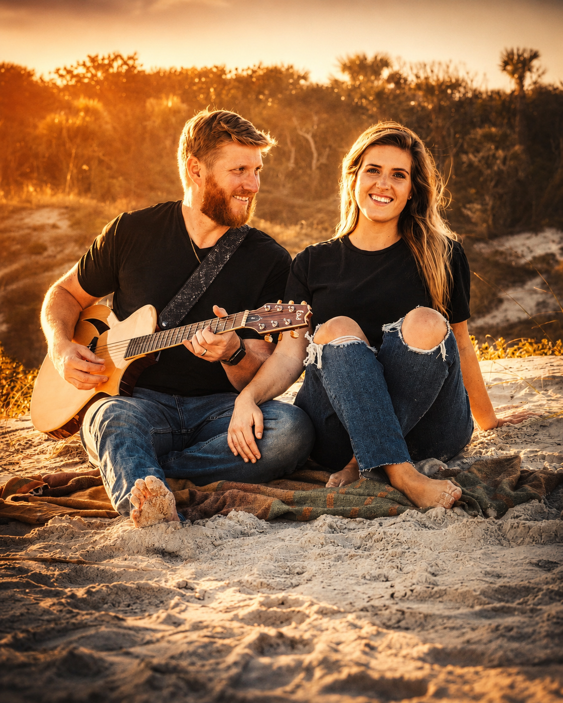 a man and woman sitting on sand with guitar