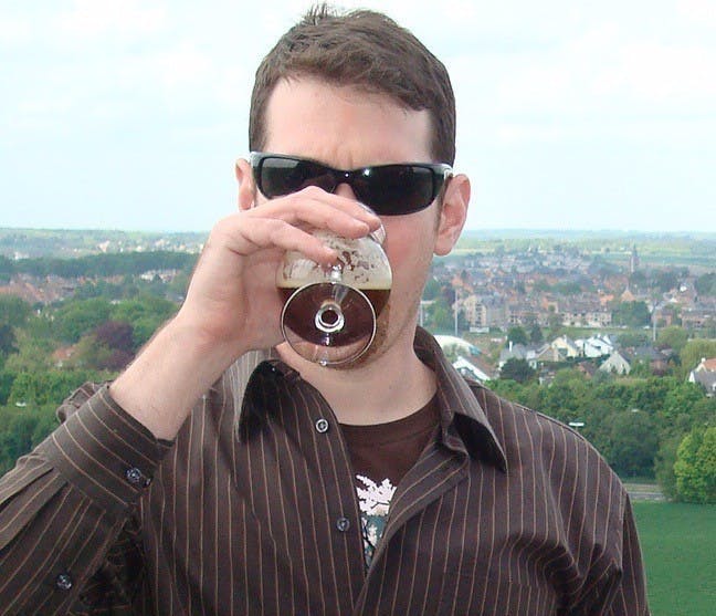 a man wearing sunglasses and holding wine glasses