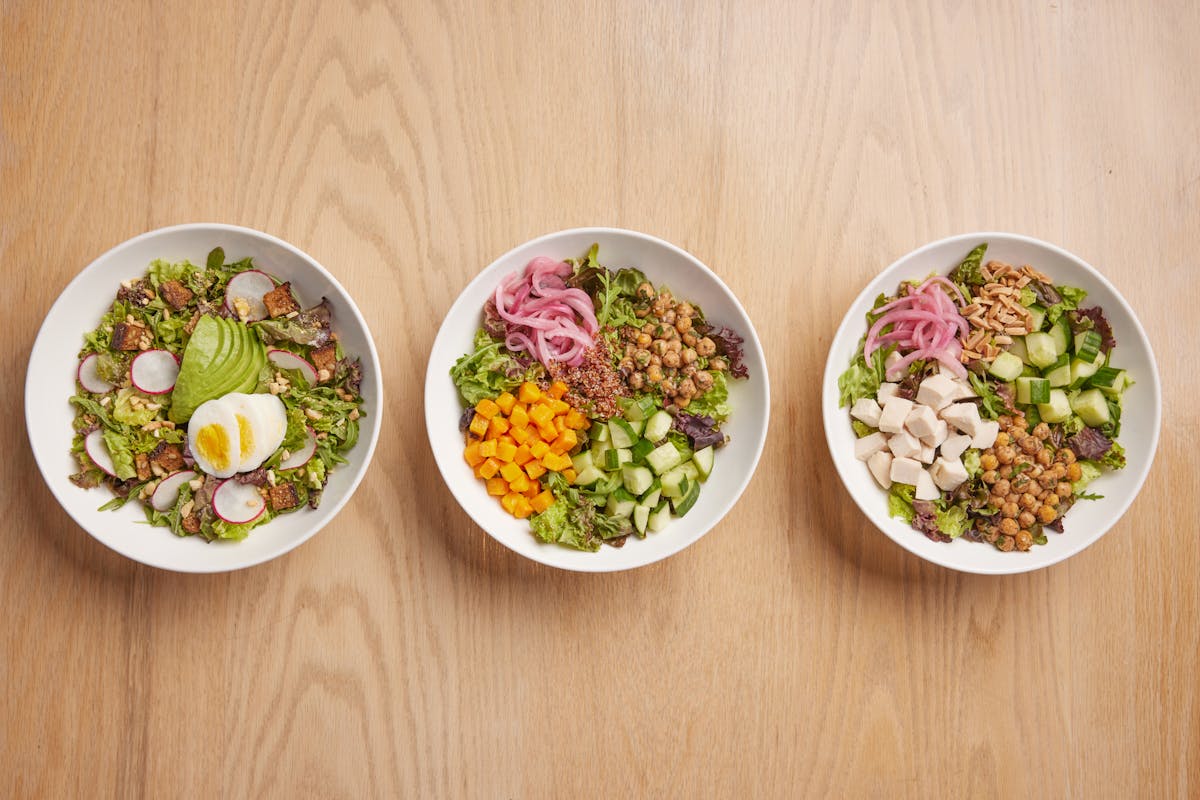 salads plated in bowls on a wooden table