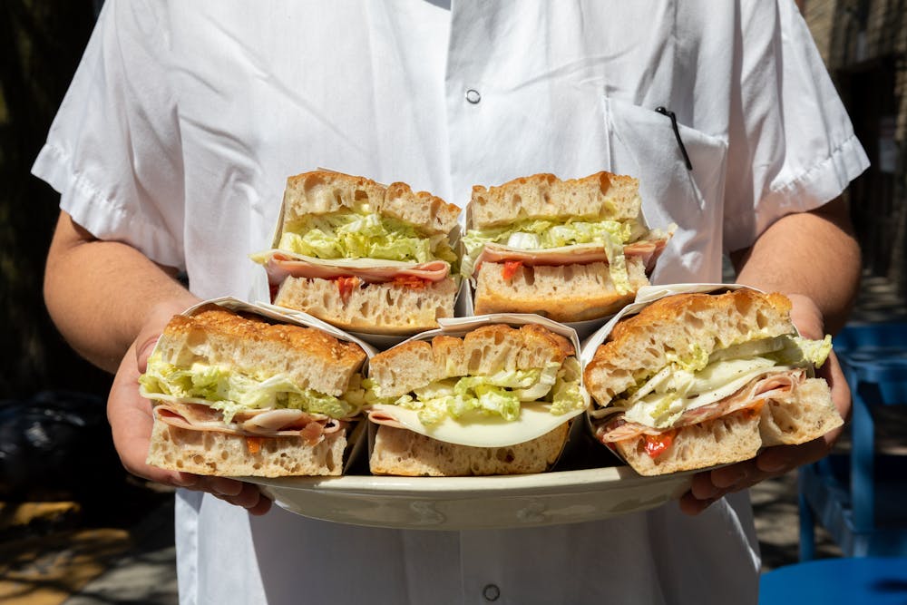 a man holding a platter of sandwiches
