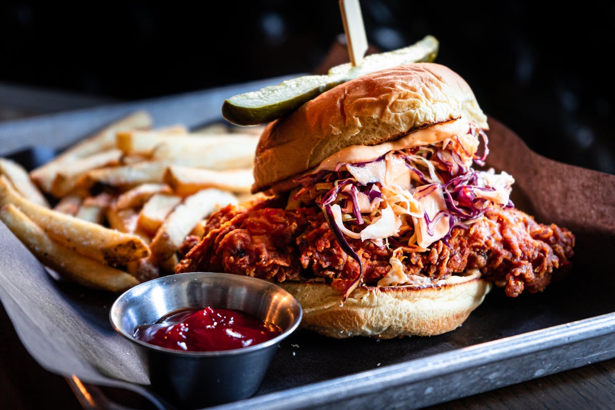 fried chicken sandwich with pickle on top. side of fries