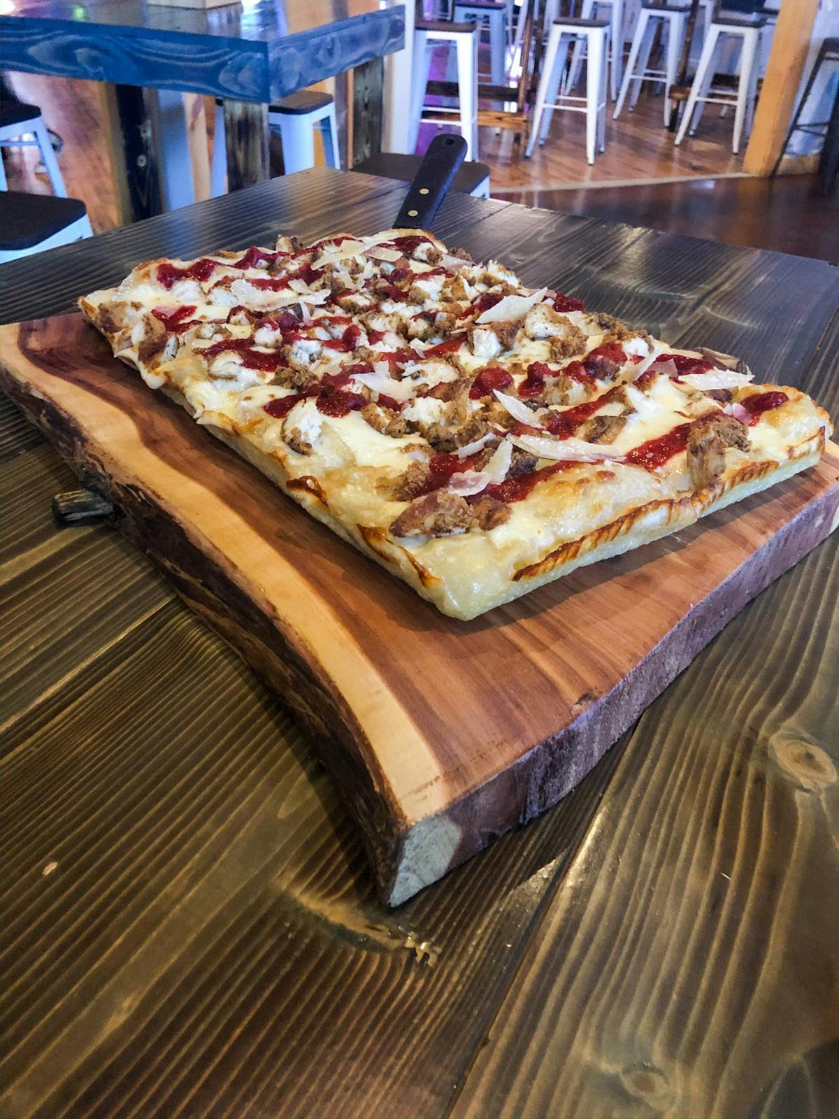 a pizza sitting on top of a wooden cutting board