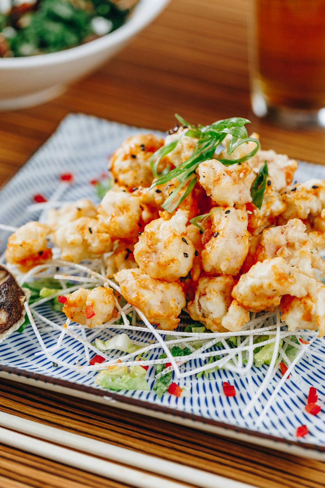 a plate topped with a lot of breaded shrimps and cilantro on top