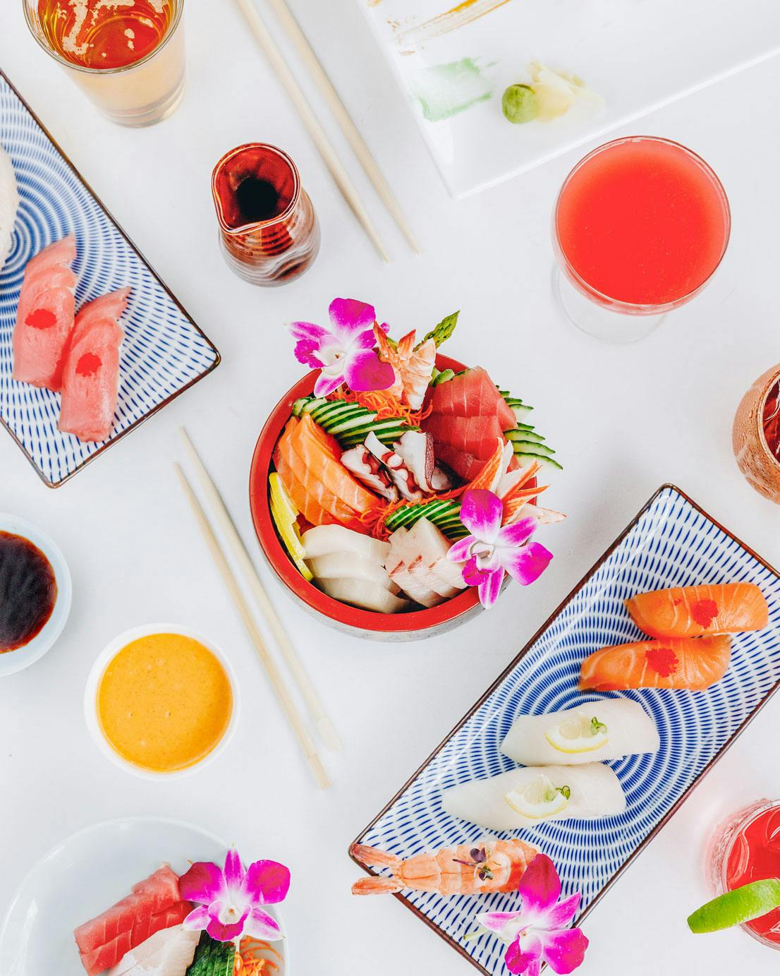 a table topped with plates of food filled with sushi, shrimps and fish