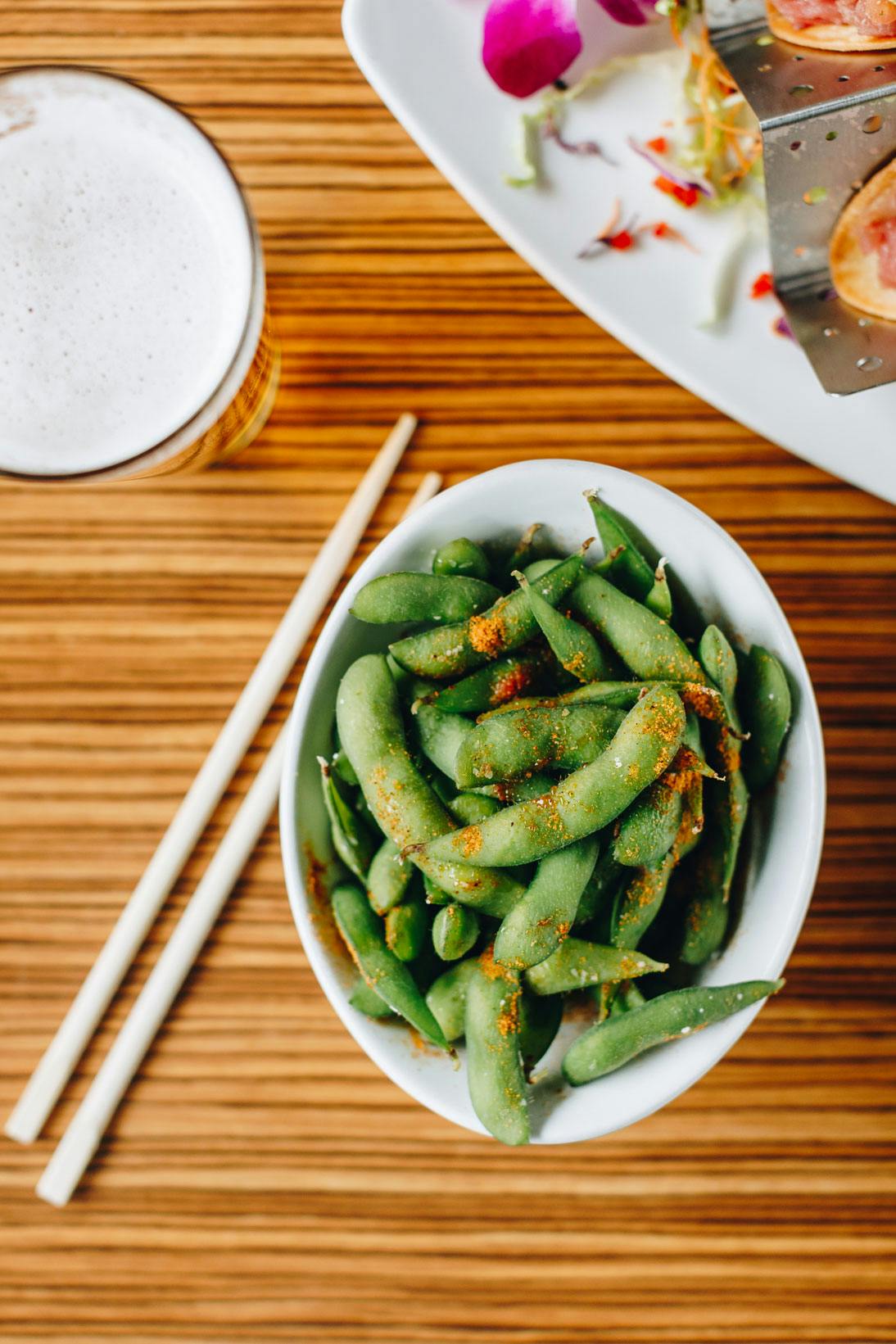 a bowl filled in with green peas sitting on a wooden table