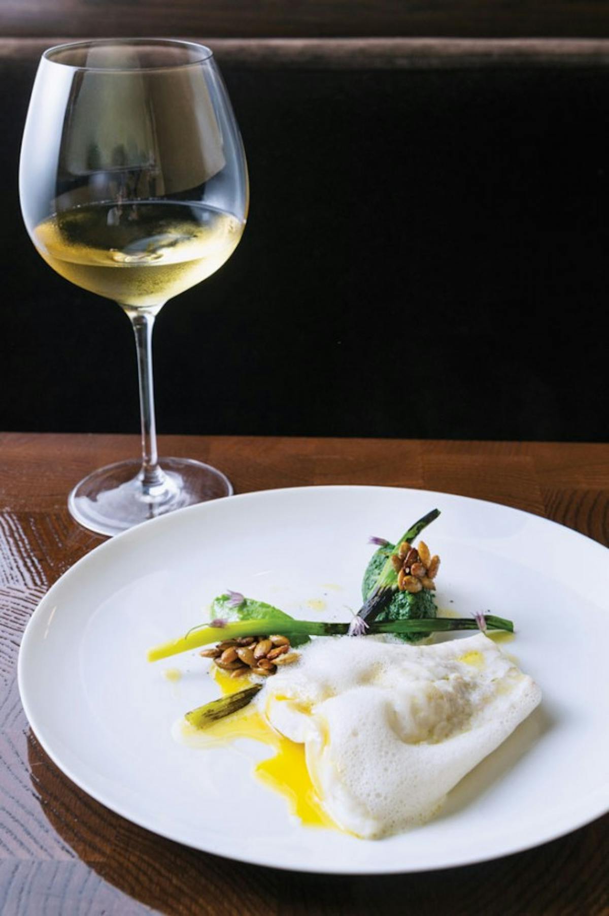 a white plate topped with food next to a glass of wine