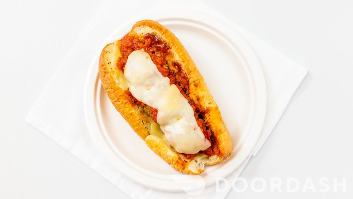 meatball sub with cheese and red sauce on a paper plate with a blank white backgorund